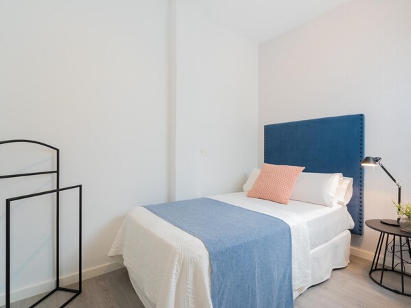 Quarto bem arrumado com uma cama, mesa de cabeceira e abajur.