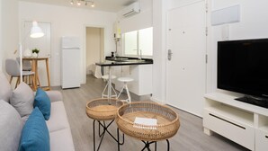 Een modern, goed verlicht appartement met een zithoek, keuken en eetgedeelte.