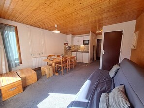 A compact living space with a kitchenette, dining area, and a sofa.