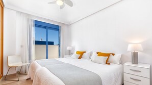 Ett hotellrum med en stor säng, ett skrivbord, en stol, ett nattduksbord och ett fönster med gardiner.