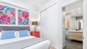 Een moderne slaapkamer met een bed, nachtkastje, lamp en een groot bloemenkunstwerk aan de muur.