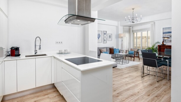 Een moderne keuken met witte kasten, een centraal eiland en een roestvrijstalen afzuigkap.