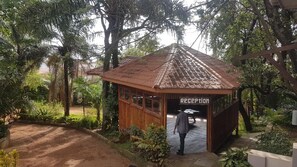 Una caseta de recepción de madera con techo de tejas, rodeada de exuberante follaje y árboles.