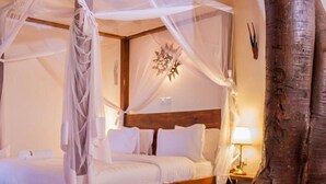 Una habitación con una cama bajo dosel, una mesita de noche con lámpara y un adorno en la pared.