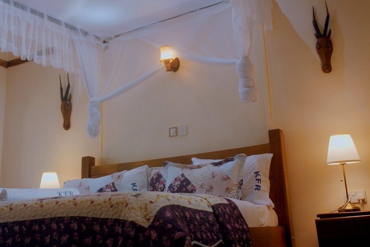 Une chambre d’hôtel comprenant un lit, une table de chevet, une lampe, un lit à baldaquin et des œuvres d’art décoratives sur les murs.