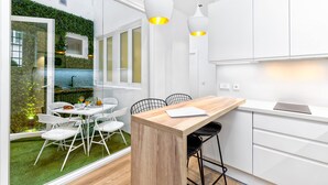 Una cocina moderna con armarios blancos, una isla de madera y un comedor con sillas blancas.