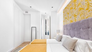 Habitación de hotel con una cama grande, un armario, un espejo y una pared con un diseño amarillo.