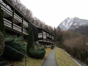 A building with multiple balconies, a pathway, and a mountainous backdrop.
