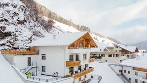 Ein schneebedecktes Bergresort mit mehrstöckigen Gebäuden, die Balkone und Holzhäuschenfassaden haben.