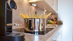 A kitchen with a pasta maker, a pot of spaghetti, and a stove.