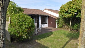 A house with a tiled roof, a front porch, and a lawn. - The Happy House (De Haan)