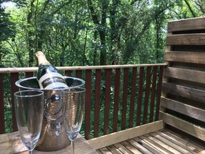 A wooden deck with a metal bucket containing a bottle and two glasses. - Goldcrest 4 Hot Tub (Carmarthen)