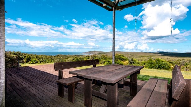 Une terrasse en bois avec une table et des bancs, offrant une vue sur un paysage magnifique.