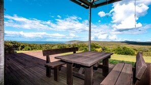 Une terrasse en bois avec une table et des bancs, offrant une vue sur un paysage magnifique.