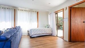 Une chambre à coucher avec un lit, un canapé bleu, un plancher en bois et une porte en bois.