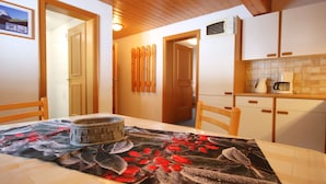 A cozy kitchen with wooden cabinets, a table with a floral tablecloth, and a microwave above the counter. - Nice apartment for 5 guests with WIFI, TV, patio and pets allowed (Gaschurn)