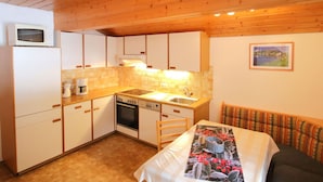 A compact kitchen with white cabinets, a microwave, a coffee maker, and a dishwasher. There is a wooden ceiling and a small window with a view of a mountain. - Nice apartment for 5 guests with WIFI, TV, patio and pets allowed (Gaschurn)