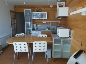 Une cuisine compacte avec un mur en bois, un four à micro-ondes, une machine à café et un évier.