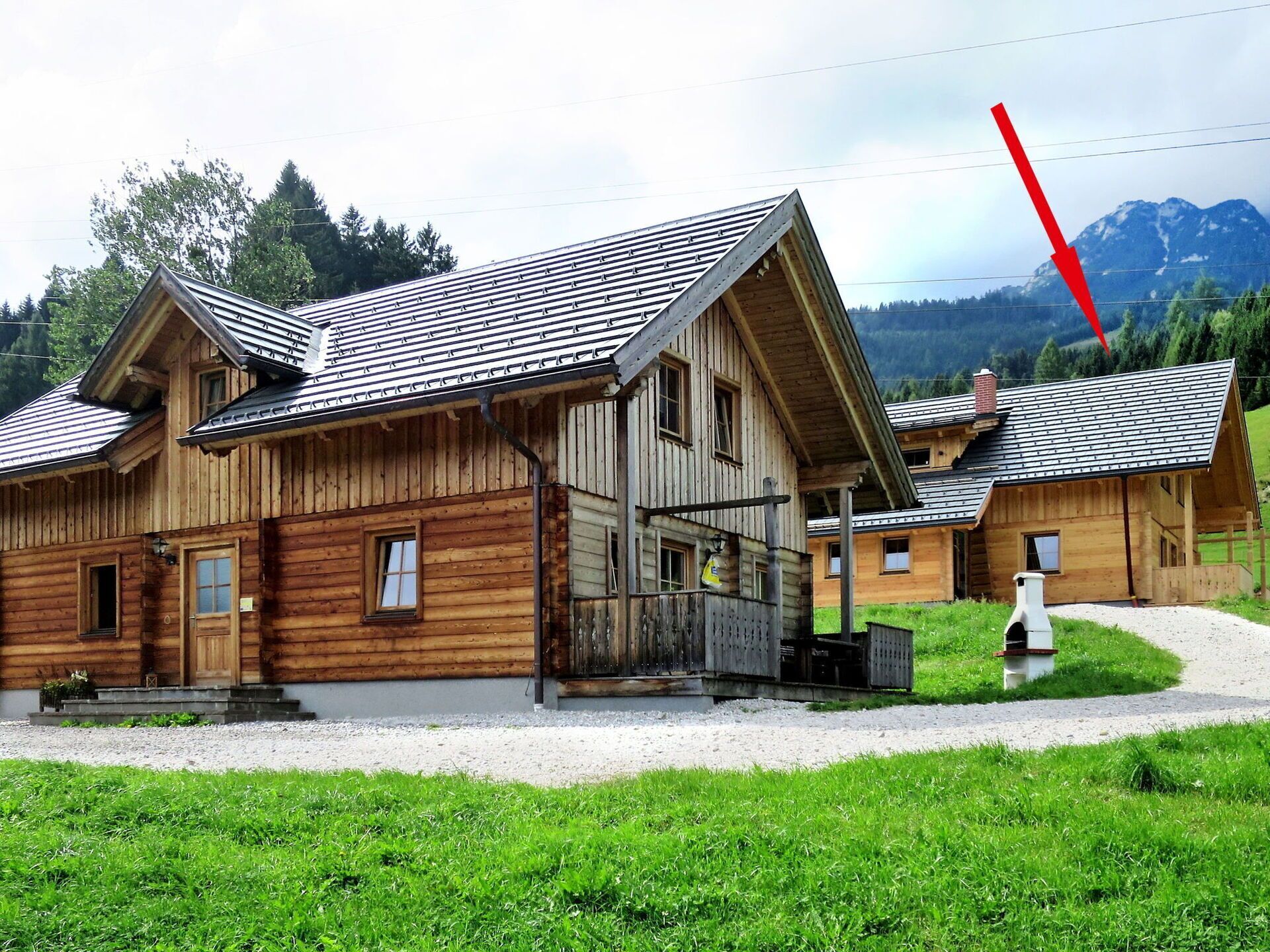A wooden cabin with a sloped roof, a porch, and a gravel driveway.