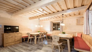 A wooden interior with a dining table, chairs, a TV, and a bench. - Cosy apartment in villa for 18 guests with WIFI, pool, TV, terrace and pets allowed (Klazenberg)