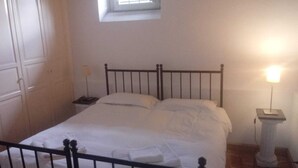 Un lit bien fait dans une chambre avec une fenêtre, une table de chevet et une commode.