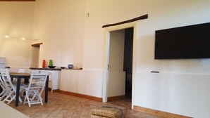 Une cuisine équipée d’une table à manger, de chaises et d’un téléviseur fixé au mur.