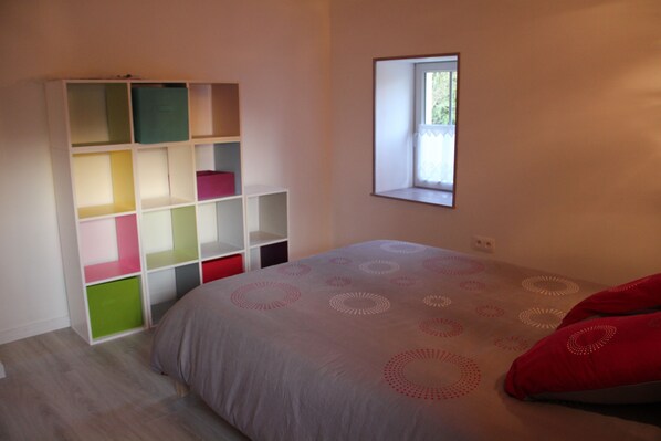 A bedroom with a bed, a window, and a built-in bookshelf with multiple compartments.