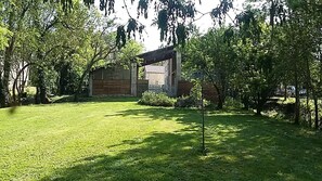 A wooden building with a covered entrance, surrounded by trees and a well-maintained lawn.