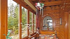 Una stanza accogliente con ampie finestre, un termosifone, un divano colorato con motivo decorativo e un'elegante composizione floreale appesa.