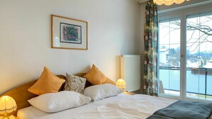 Une chambre d’hôtel avec un lit, des oreillers, un tableau encadré au mur, un radiateur et une vue par la fenêtre.