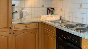 Une cuisine avec des meubles de rangement en bois, un évier en acier inoxydable, une cuisinière et une machine à café.