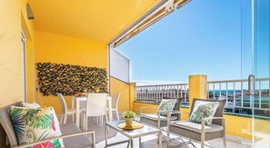 A balcony with a yellow wall, a wicker sofa set, a small table, and a view of the sea. - Penthouse in the center of La Cala and a step away from Playa! (La Cala de Mijas)