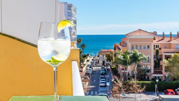 A balcony with a clear view of the sea and buildings.