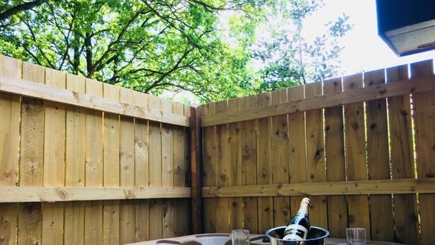 A hot tub with champagne and glasses, surrounded by a wooden fence. - Goldcrest 3 Hot Tub (Carmarthen)