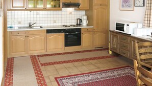 Une cuisine avec des meubles de rangement en bois, une cuisinière, un évier et un four à micro-ondes.