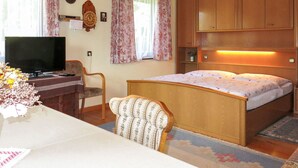 Une chambre à coucher comprenant un lit, un bureau avec une télévision, une chaise et des armoires en bois.