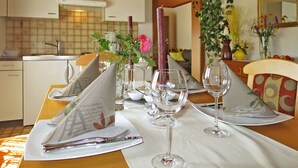 A dining table set with wine glasses, plates, and cutlery, with a vase of flowers and a candle on the table. - Cosy apartment for 4 guests with WIFI, TV, patio and pets allowed (Dietrichstein)