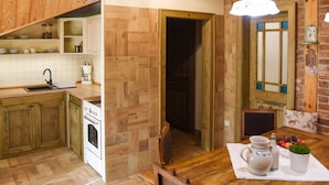 Una cocina con armarios de madera, estufa y mesa de comedor con una jarra y una planta pequeña.