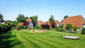 A well-maintained lawn with a swing set, a small play area, and a roundabout.