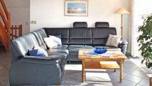 A living room with a black leather sofa, a wooden coffee table, and a lamp.