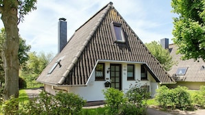Ein traditionelles Haus mit einem steilen Satteldach, einem Schornstein und einem kleinen Fenster.