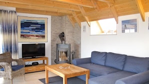 Ein gemütliches Wohnzimmer mit einem blauen Sofa, einem Holztisch, einem Fernseher und einem Kamin.