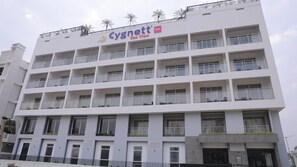 A multi-story hotel with balconies, a visible logo, and a name sign.