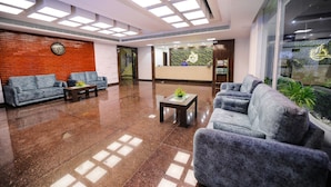 A modern lobby with a reception desk, sofas, and a large window with a view. - Cygnett Inn Sea View (Kanthi)