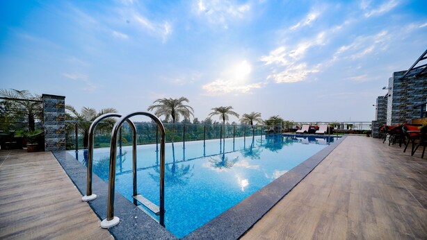 A rooftop pool with clear blue water, surrounded by wooden decking and metal railings. - Cygnett Inn Sea View (Kanthi)