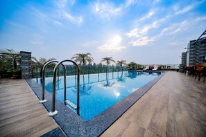 A rooftop pool with clear blue water, surrounded by wooden decking and metal railings. - Cygnett Inn Sea View (Kanthi)