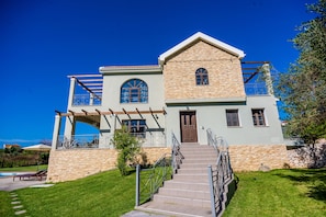 Une maison à deux étages avec une façade en pierre, un balcon en bois et une porte d’entrée.
