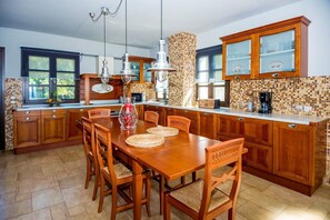 Una cocina con gabinetes de madera, salpicadero azulejado y un comedor con mesa y sillas de madera.