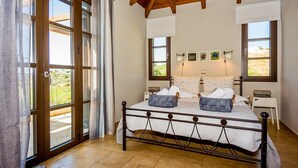 Un dormitorio con una cama, dos mesitas de noche, una ventana y una puerta.
