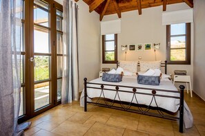 Un dormitorio con una cama, dos mesitas de noche, una ventana y una puerta.